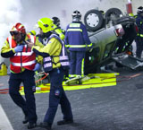 Varios sanitarios y bomberos participan en el rescate de las víctimas de un coche volcado