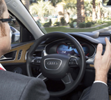 Un conductor en un vehículo de la marca Audi, con las manos lejos del volante