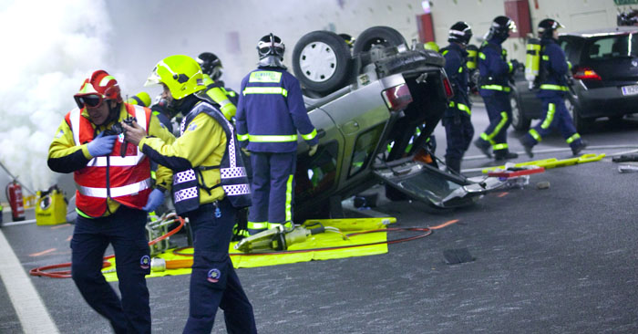 Varios sanitarios y bomberos participan en el rescate de las víctimas de un coche volcado