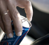 La mano de un conductor abre una lata de refrescos